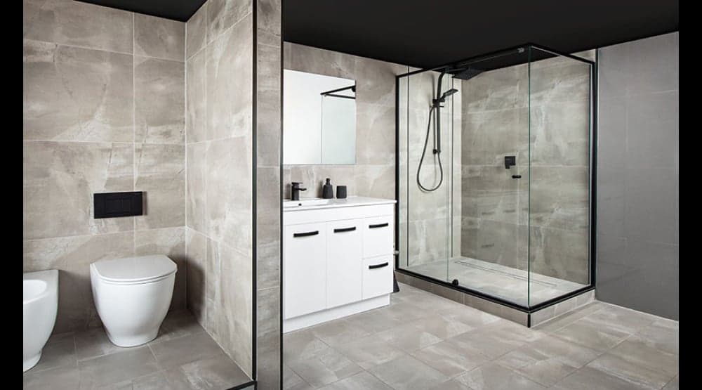 Frameless glass shower and floating vanity in a stone-tiled showroom bathroom